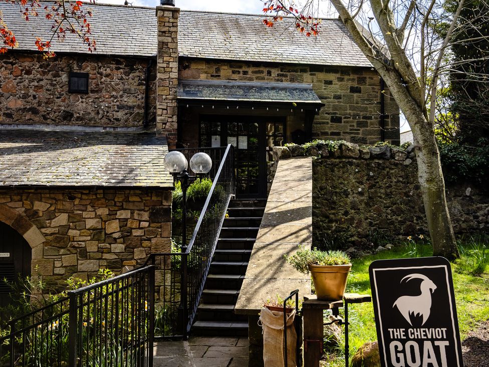 An outdoor view of a building with steps and a sign at The Cheviot Goat Akeld near Wooler