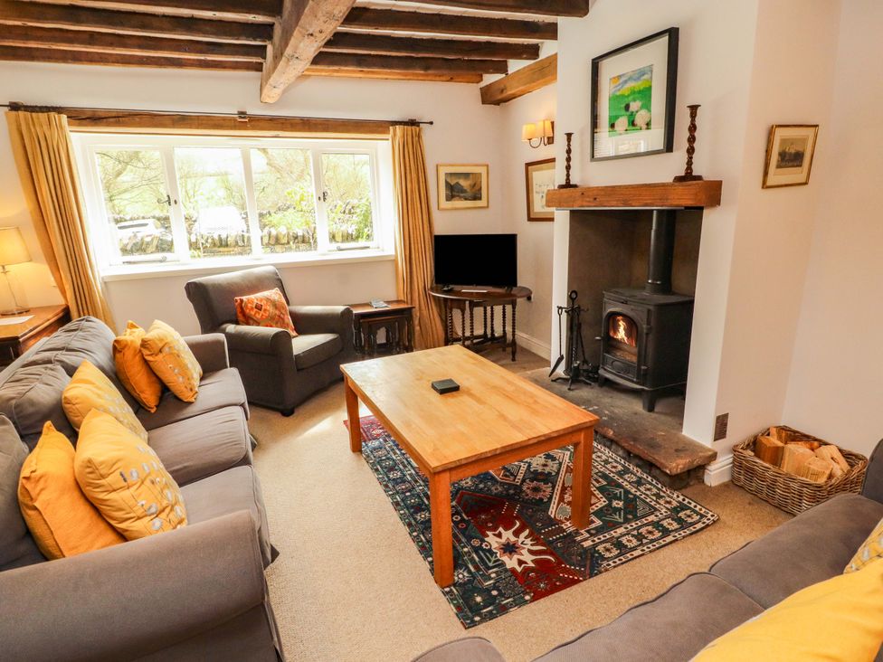 A living room with a sofa, coffee table, and fireplace at Two Town End in Mungrisdale, Mosedale