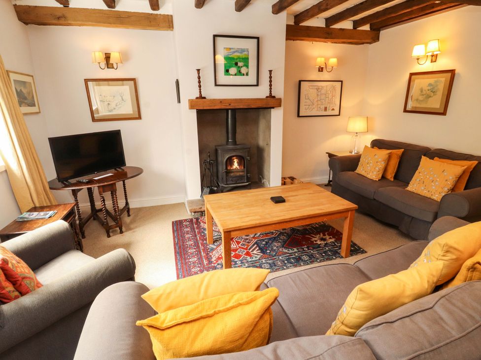 A living room with a sofa, coffee table, and fireplace at Two Town End in Mungrisdale, Mosedale