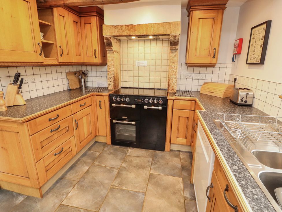A kitchen with wooden cabinets and appliances at Two Town End in Mungrisdale, Mosedale