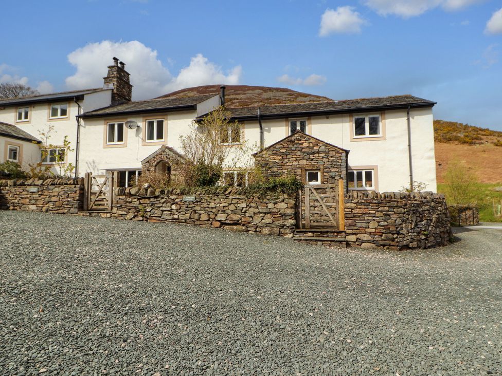 A house with a gravel driveway and stone wall at Two Town End in Mungrisdale, Mosedale