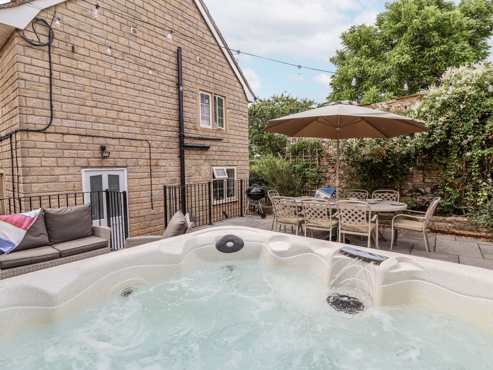 An outdoor area with a hot tub and dining set at The Stable House in Sherborne
