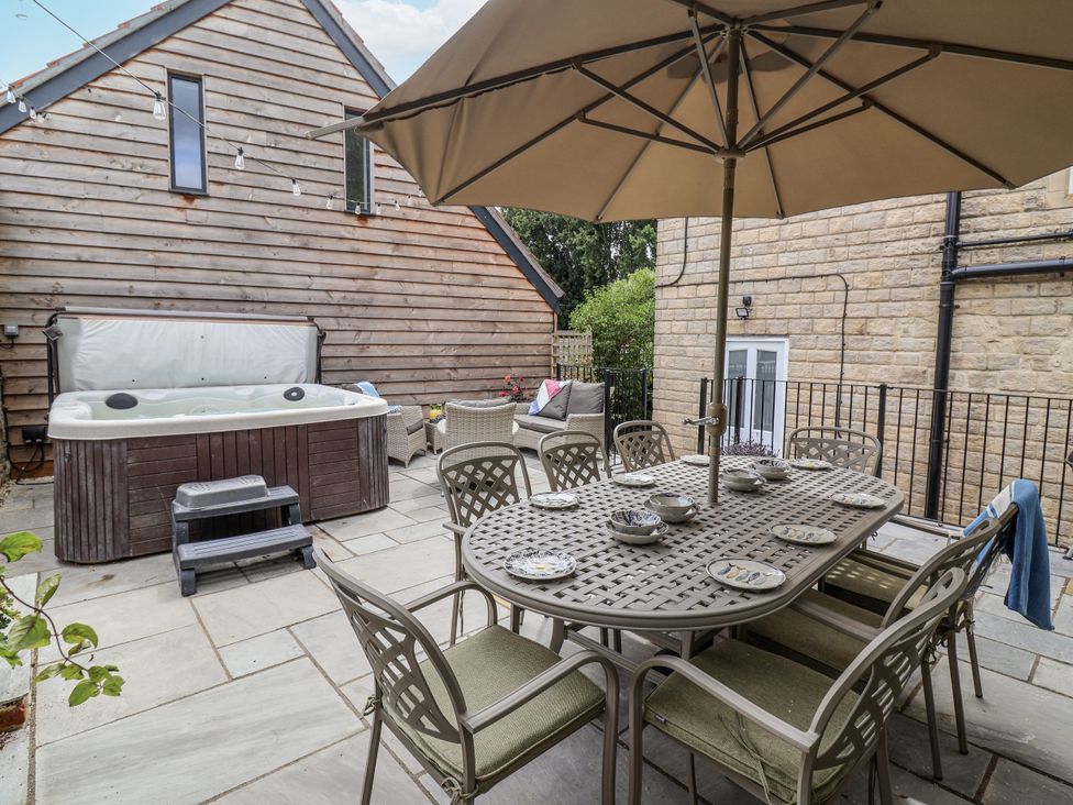 An outdoor patio with a table and chairs and a hot tub at The Stable House in Sherborne