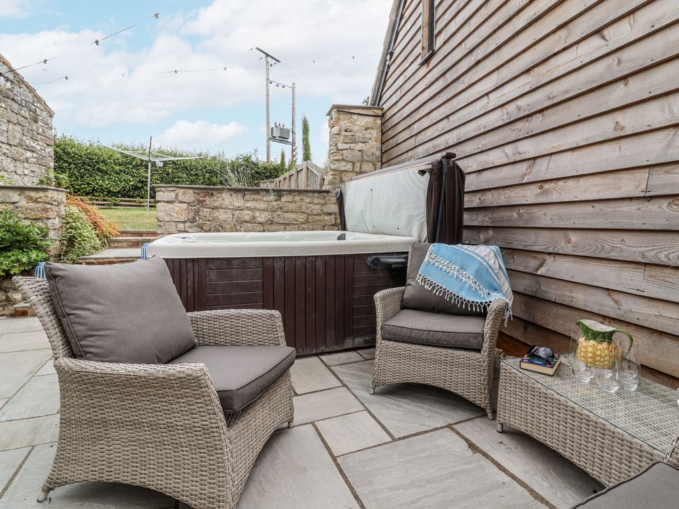 An outdoor seating area with a hot tub and chairs at The Stable House in Sherborne