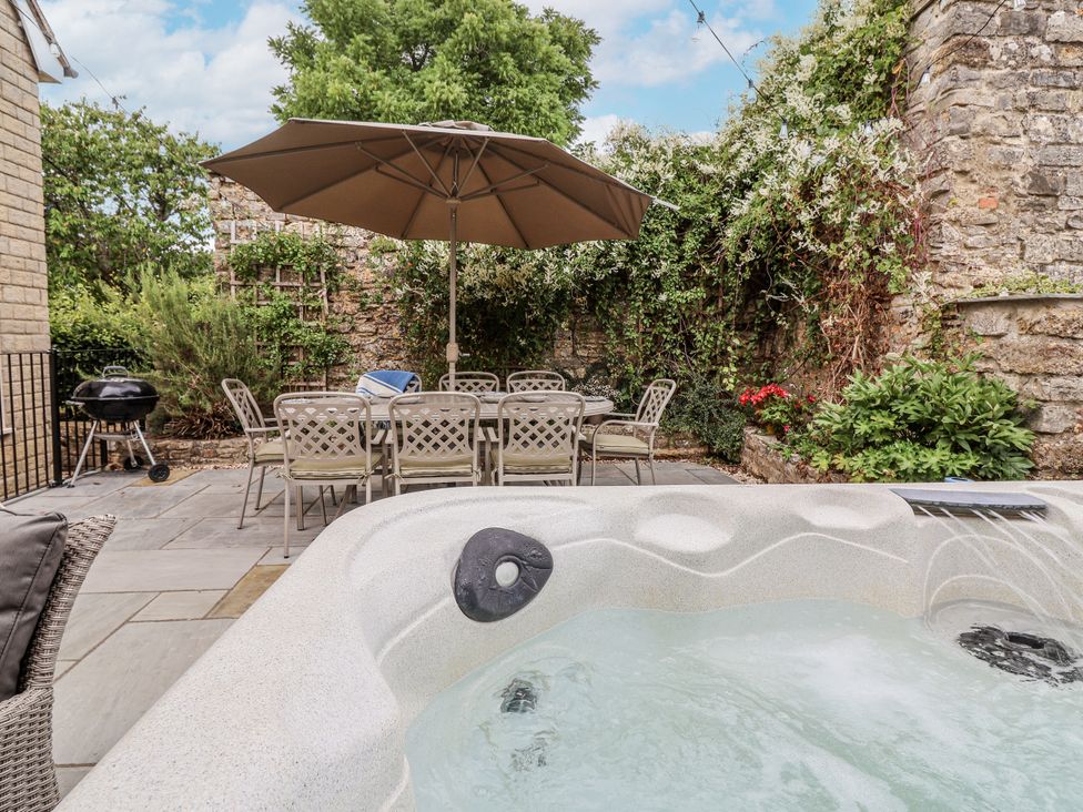 An outdoor space with a hot tub, dining table, and grill at The Stable House in Sherborne