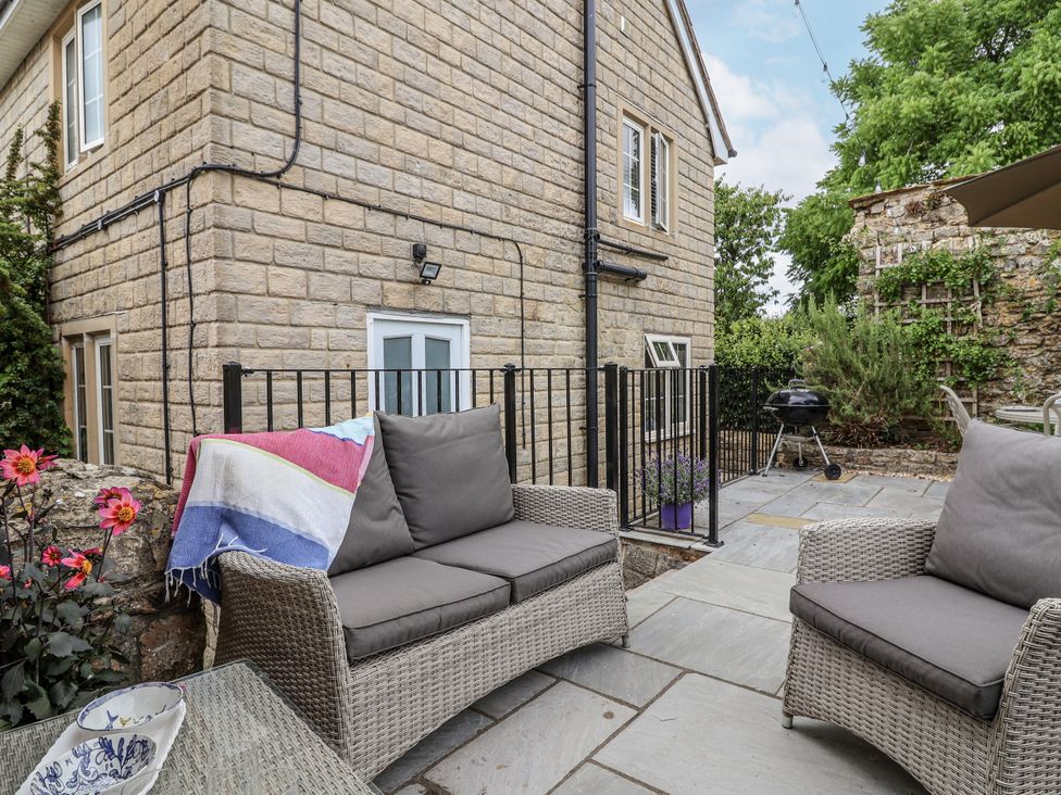 A garden with seating area and grill at The Stable House in Sherborne