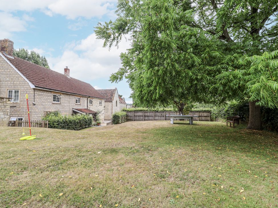 A yard with a house and trees at The Stable House in Sherborne