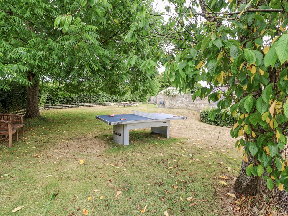 A garden with a ping pong table and a bench at The Stable House in Sherborne
