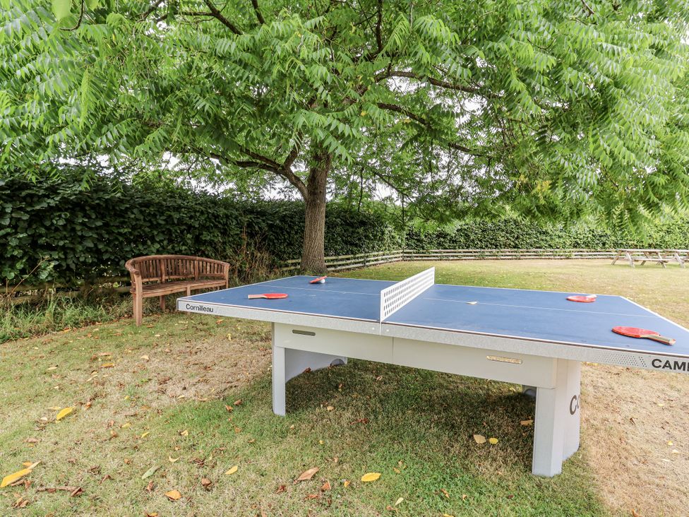 A table tennis setup under a tree with a bench at The Stable House in Sherborne
