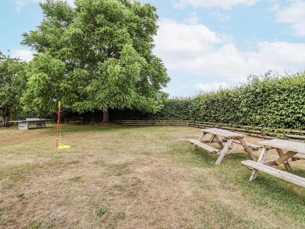 A garden with picnic tables and a tree at The Stable House in Sherborne