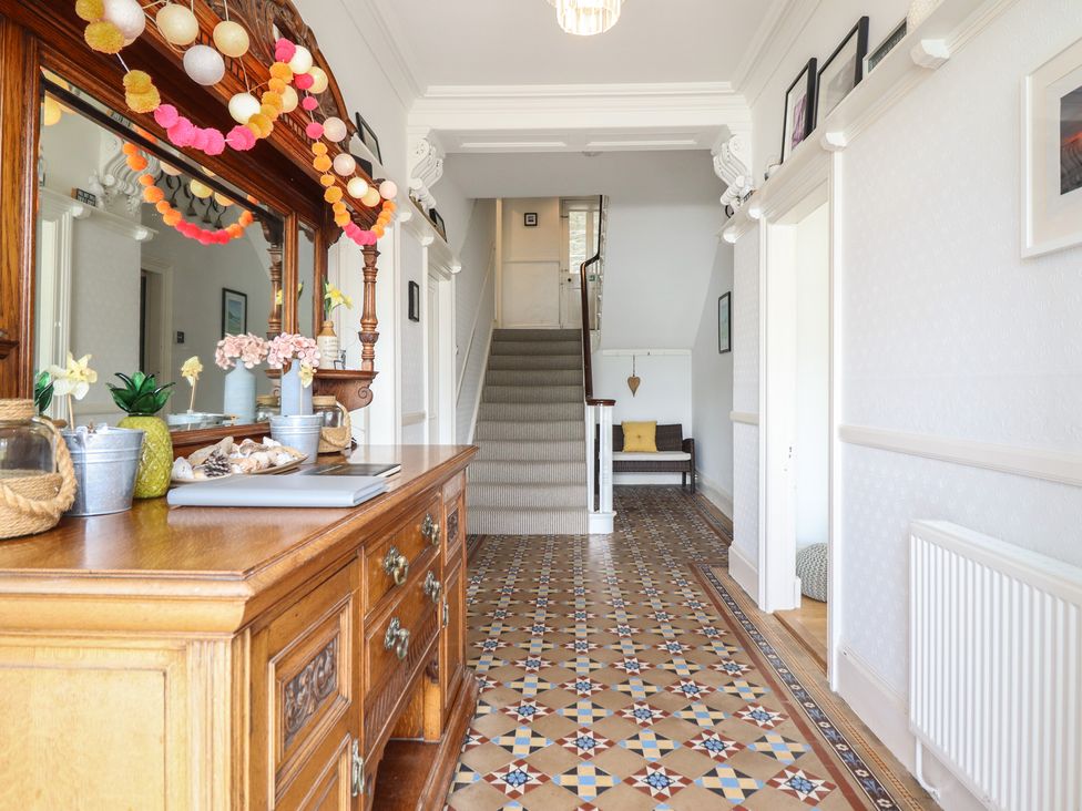 A hallway with a staircase and console table at 5 Porkington Terrace in Barmouth