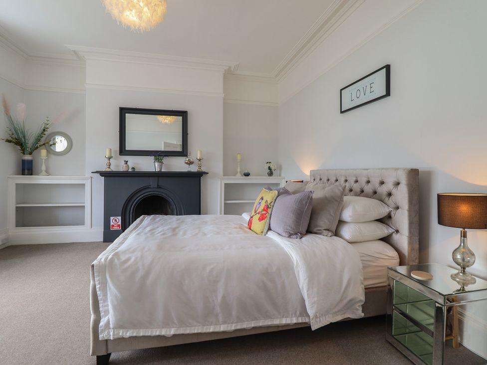 A bedroom with a bed and a fireplace at 5 Porkington Terrace in Barmouth