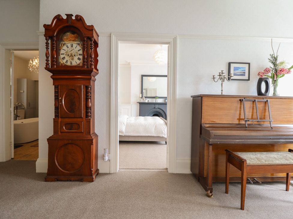 A living room with a grandfather clock and a piano at 5 Porkington Terrace in Barmouth