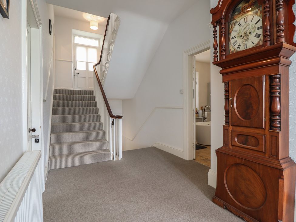 A hallway with a staircase and a clock at 5 Porkington Terrace Barmouth