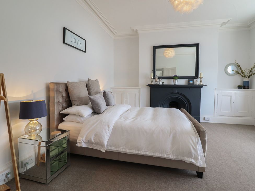 A bedroom with a bed and a mirror at 5 Porkington Terrace in Barmouth