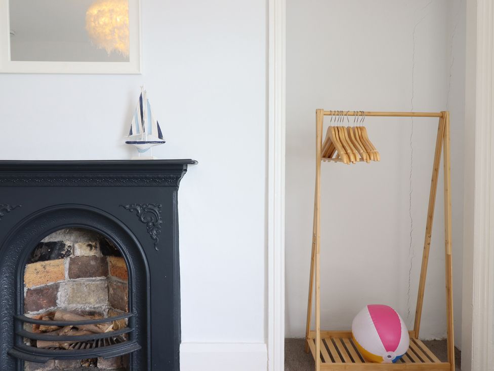 A living room with a fireplace and clothing rack at 5 Porkington Terrace in Barmouth