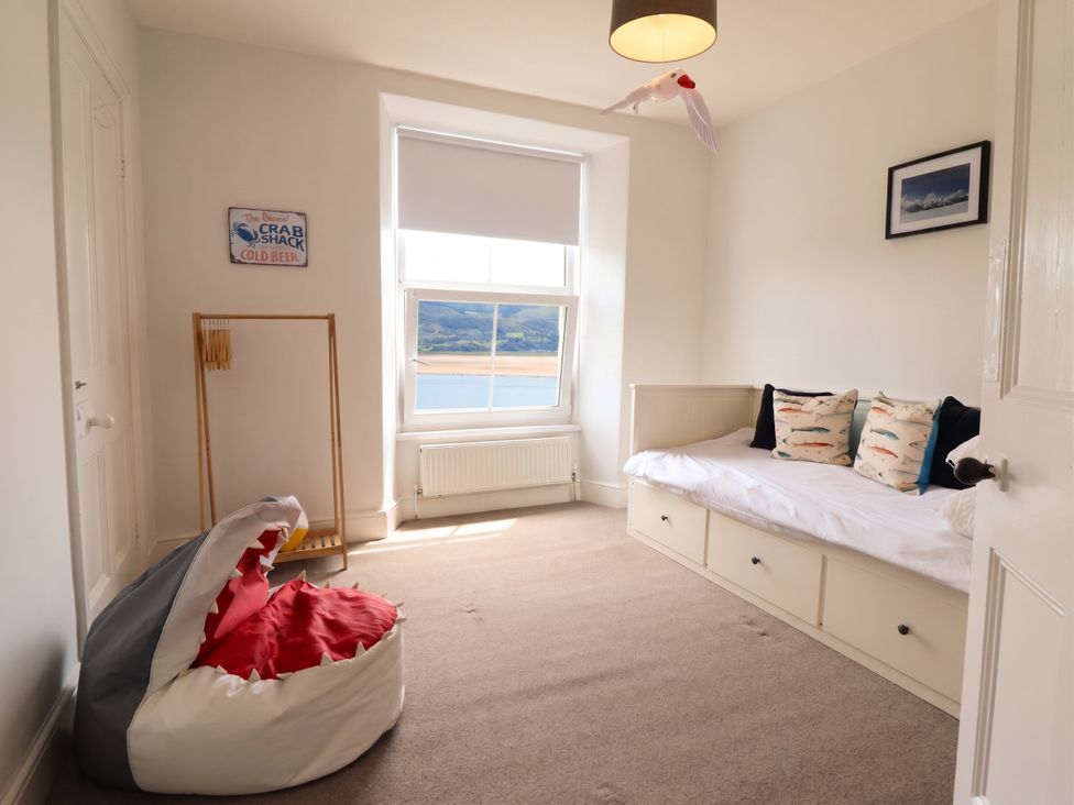 A bedroom with a bed and shark chair at 5 Porkington Terrace Barmouth