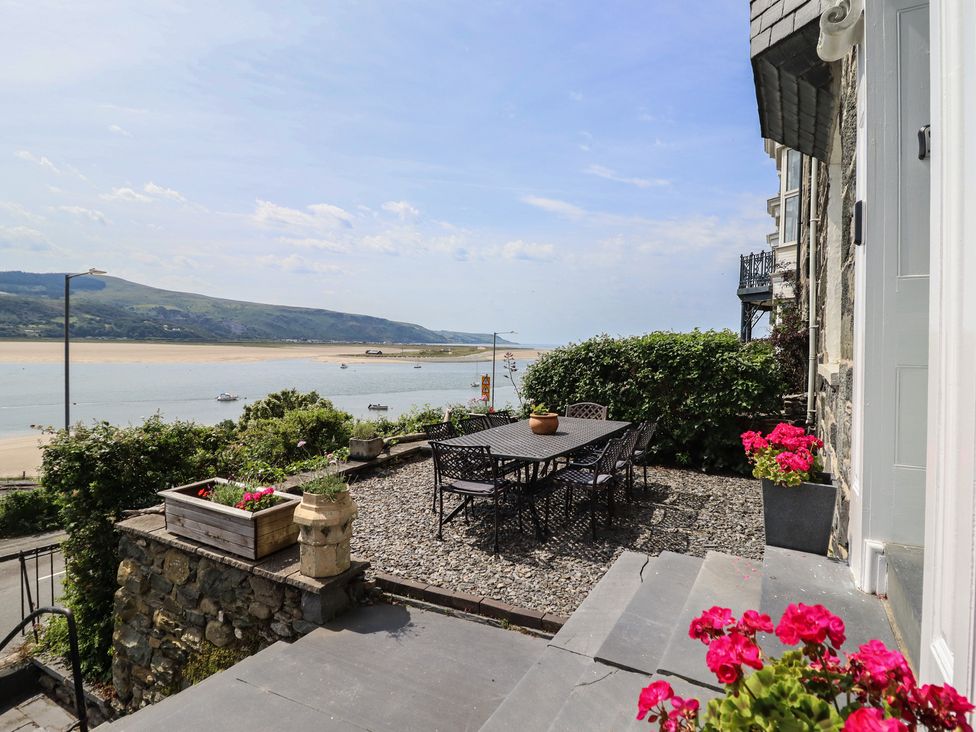 An outdoor patio with a table and chairs overlooking a bay at 5 Porkington Terrace in Barmouth