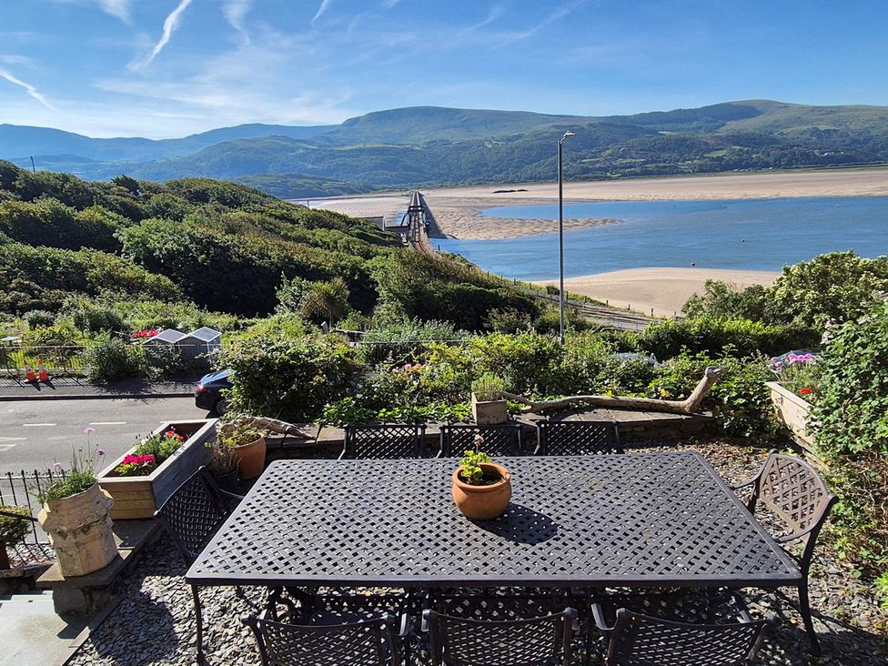 An outdoor area with a table and chairs overlooking a river at 5 Porkington Terrace in Barmouth