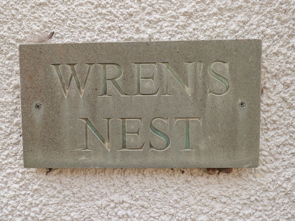 A sign displaying the name WREN'S NEST at Wrens Nest in Slapton