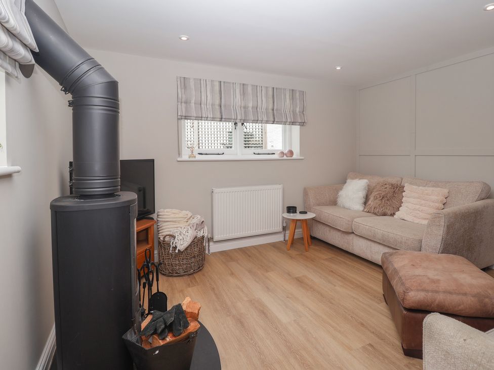 A snug with a wood stove and sofa at Wrens Nest in Slapton