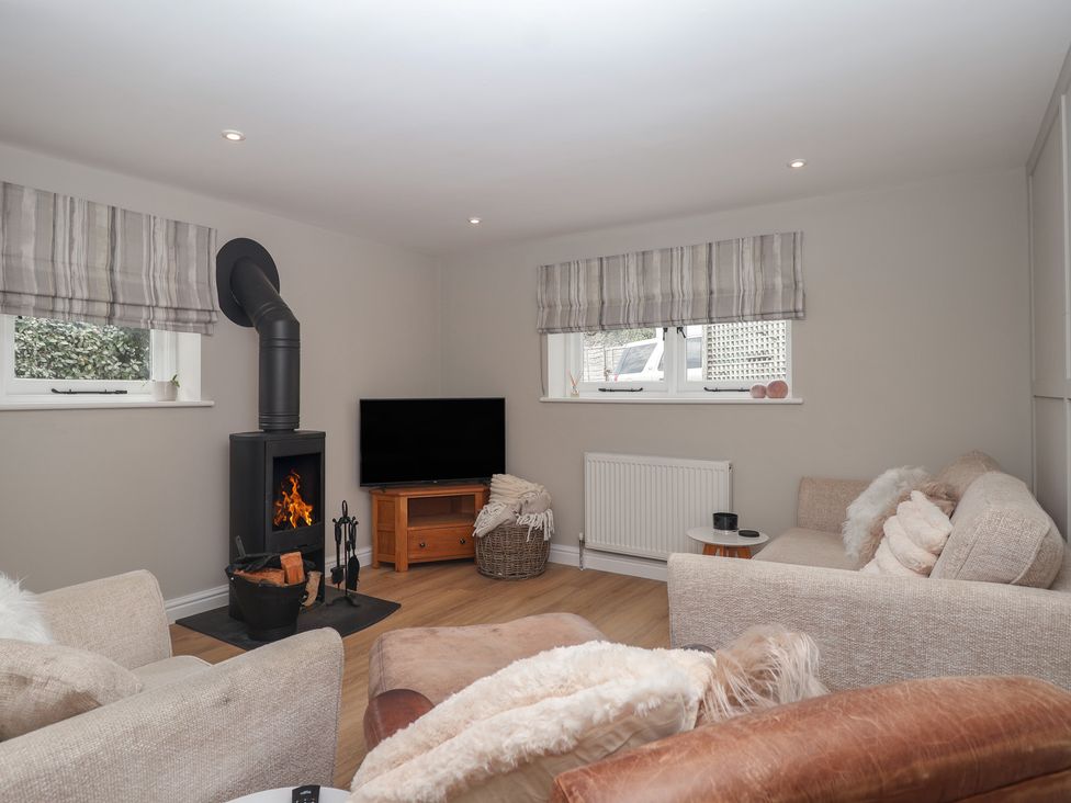 A living room with a wood burner and television at Wrens Nest in Slapton