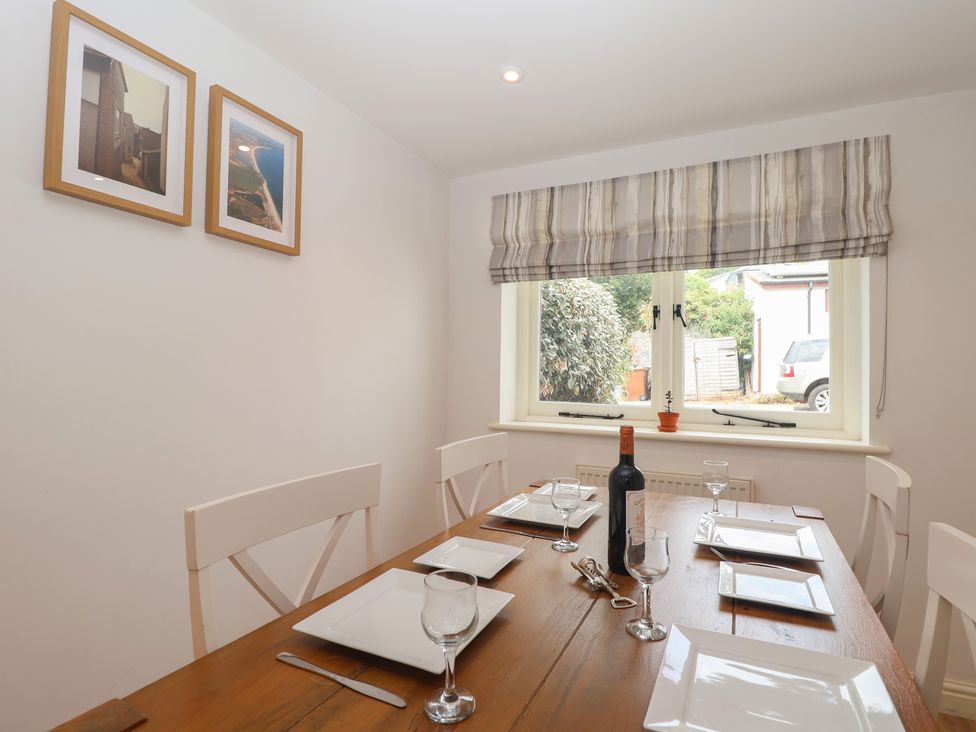 A dining room with a table set for meals at Wrens Nest in Slapton