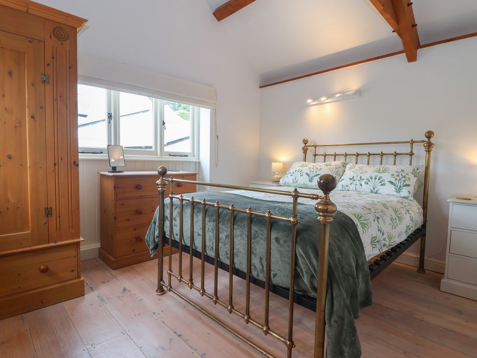 A bedroom with a bed and wardrobe at Wrens Nest in Slapton