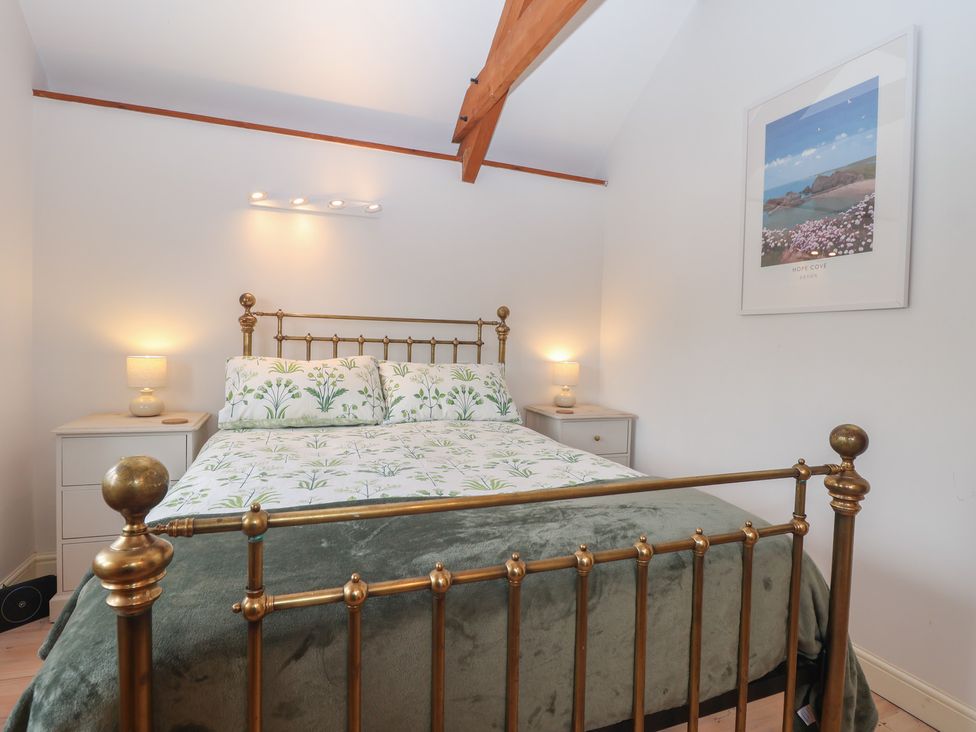 A bedroom with a brass bed and bedside table at Wrens Nest in Slapton