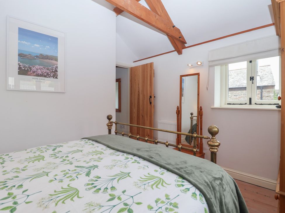 A bedroom with a bed and a mirror at Wrens Nest in Slapton