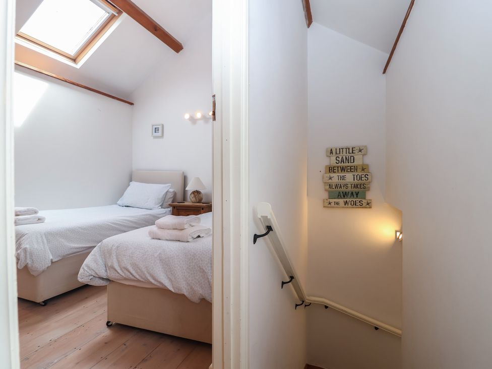 A bedroom with two beds and a staircase at Wrens Nest in Slapton
