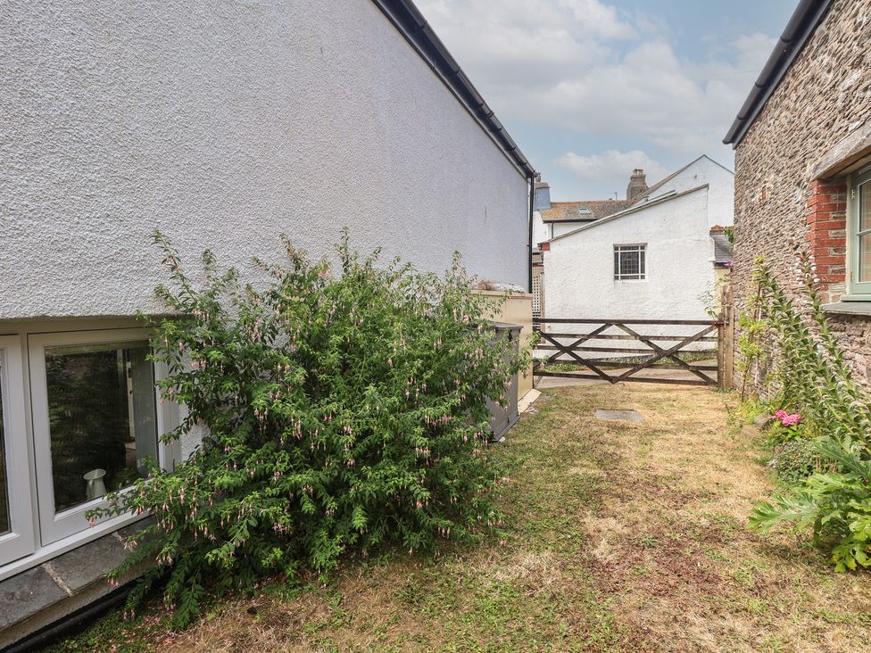 A garden with a bush and a fence at Wrens Nest in Slapton
