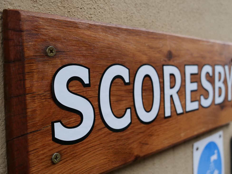 A wooden sign displaying the word Scoresby at Scoresby Cottage @ Summerfield Farm, Hawsker