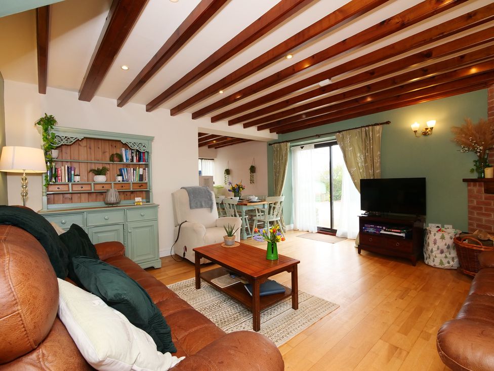 A living room with a sofa, coffee table, and television at Scoresby Cottage @ Summerfield Farm, Hawsker