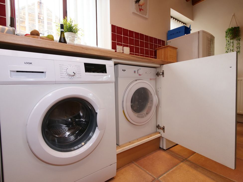 A laundry room with a washing machine and dryer at Scoresby Cottage @ Summerfield Farm, Hawsker