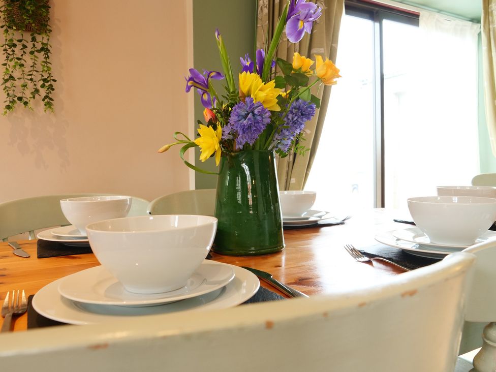 A dining room with a table set and flowers at Scoresby Cottage @ Summerfield Farm, Hawsker