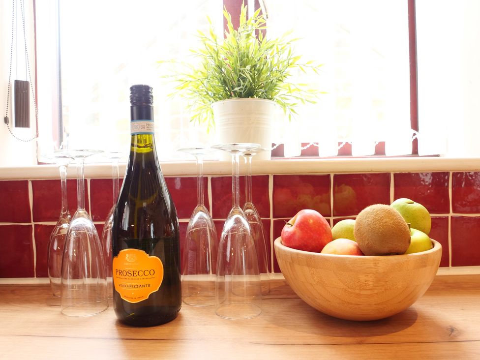 A kitchen with a bottle of prosecco and a fruit bowl at Scoresby Cottage @ Summerfield Farm, Hawsker