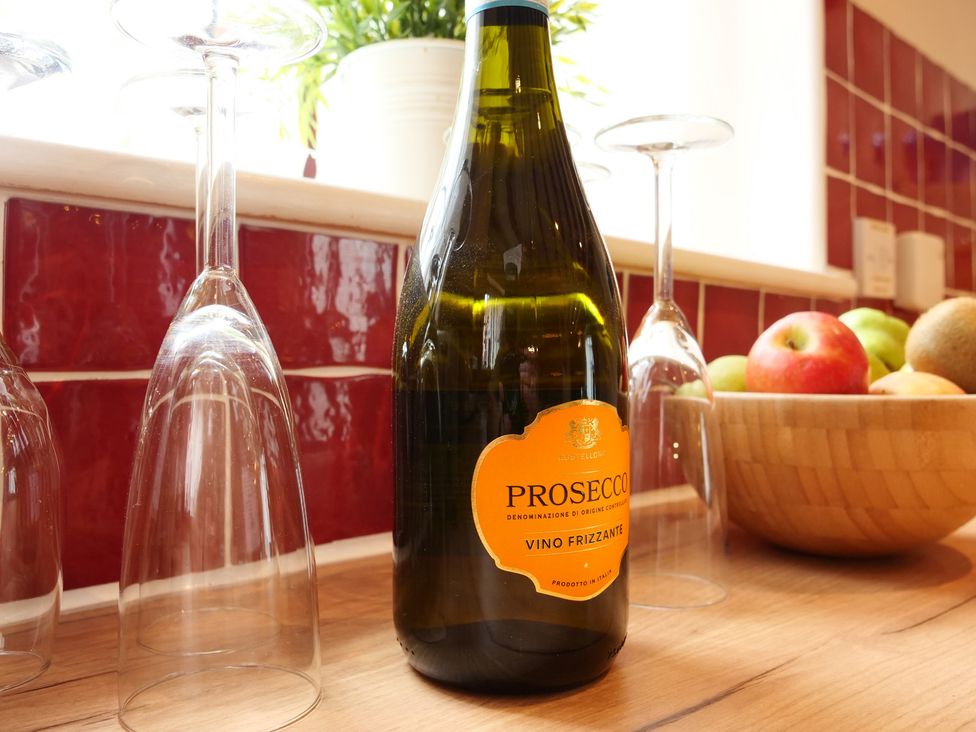 A bottle of prosecco and wine glasses on a kitchen countertop at Scoresby Cottage @ Summerfield Farm, Hawsker