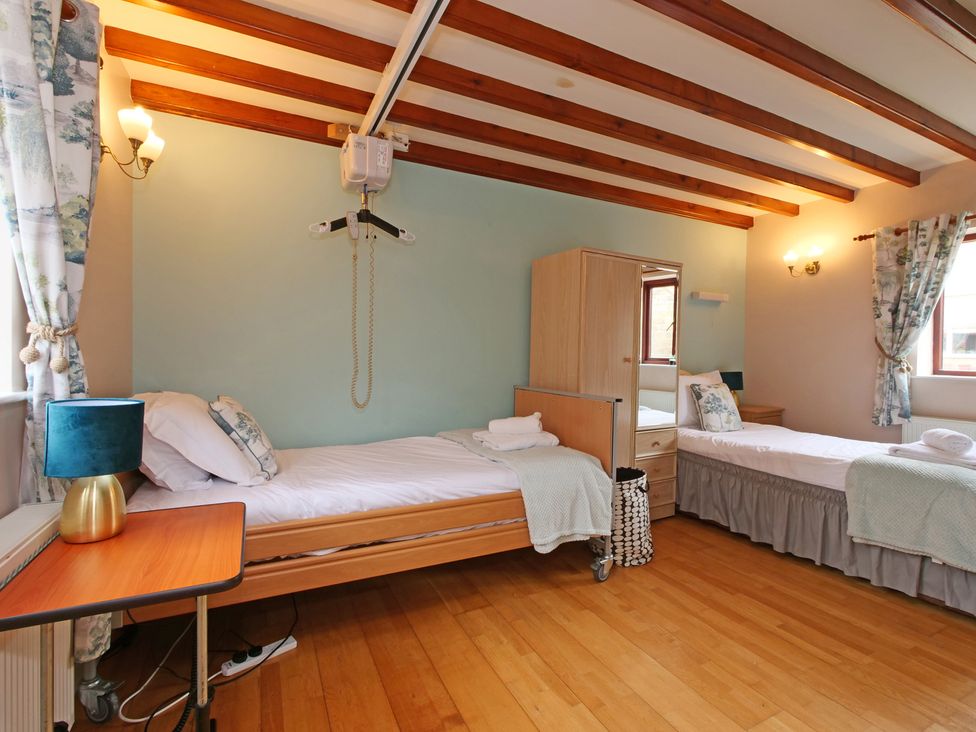 A bedroom with two beds and a wardrobe at Scoresby Cottage @ Summerfield Farm, Hawsker