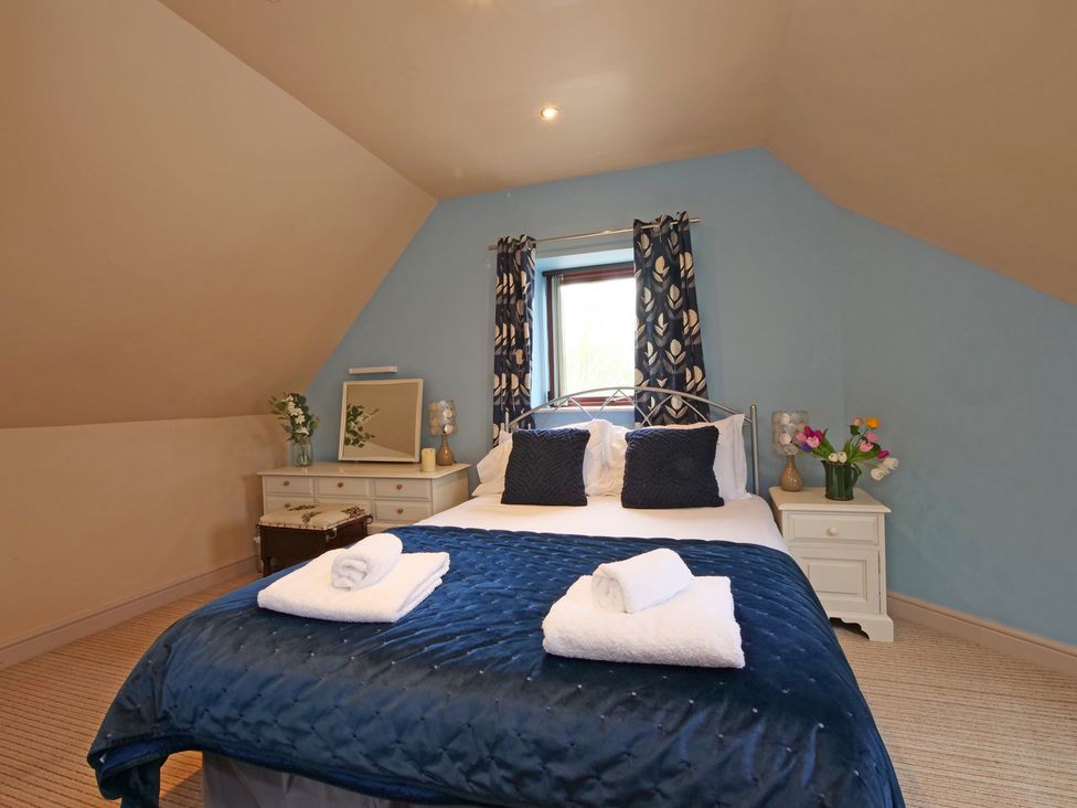 A bedroom with a bed and side table at Scoresby Cottage @ Summerfield Farm in Hawsker
