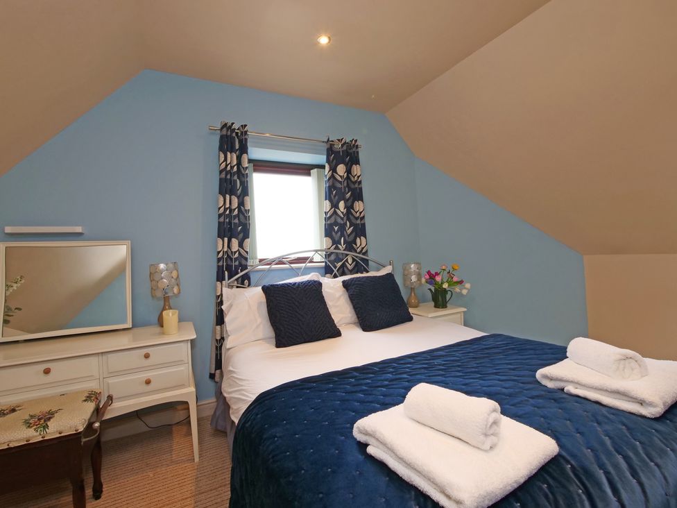 A bedroom with a bed and dressing table at Scoresby Cottage @ Summerfield Farm, Hawsker