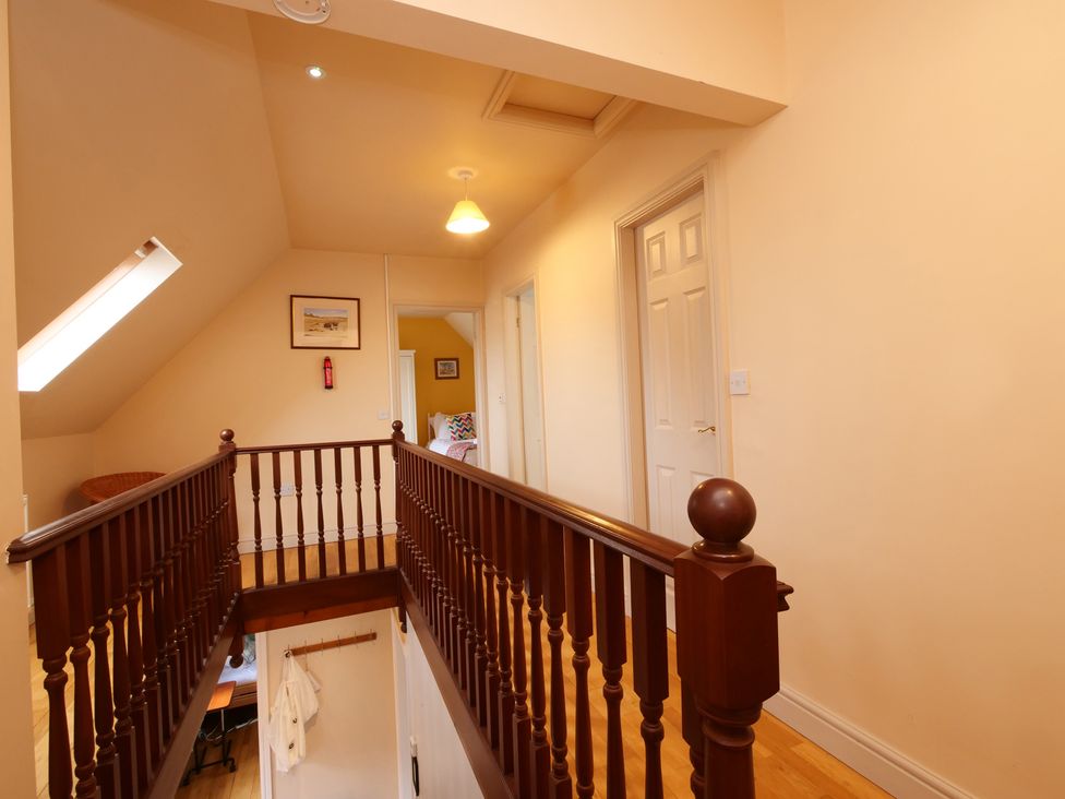 A hallway with a staircase and doors at Scoresby Cottage @ Summerfield Farm, Hawsker