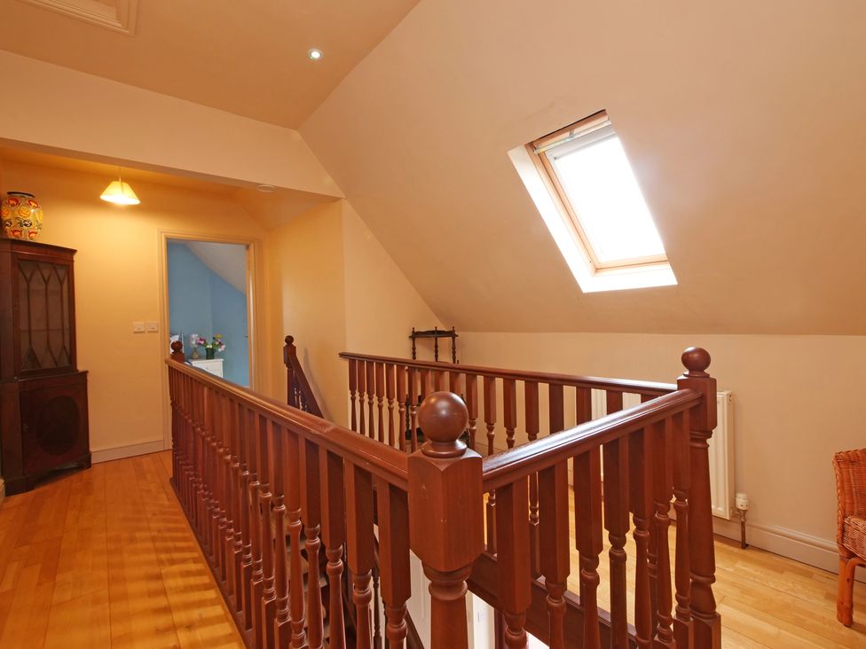 A hallway with wood banister and skylight at Scoresby Cottage @ Summerfield Farm, Hawsker