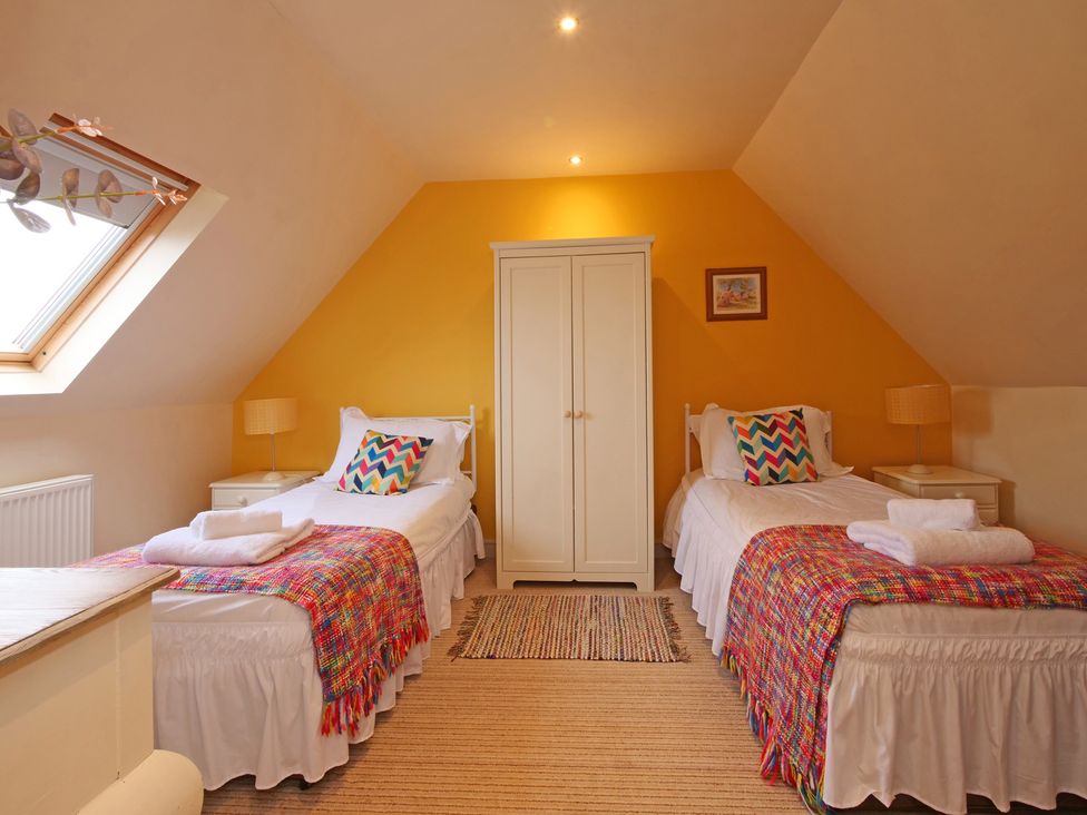 A bedroom with twin beds and a wardrobe at Scoresby Cottage @ Summerfield Farm, Hawsker