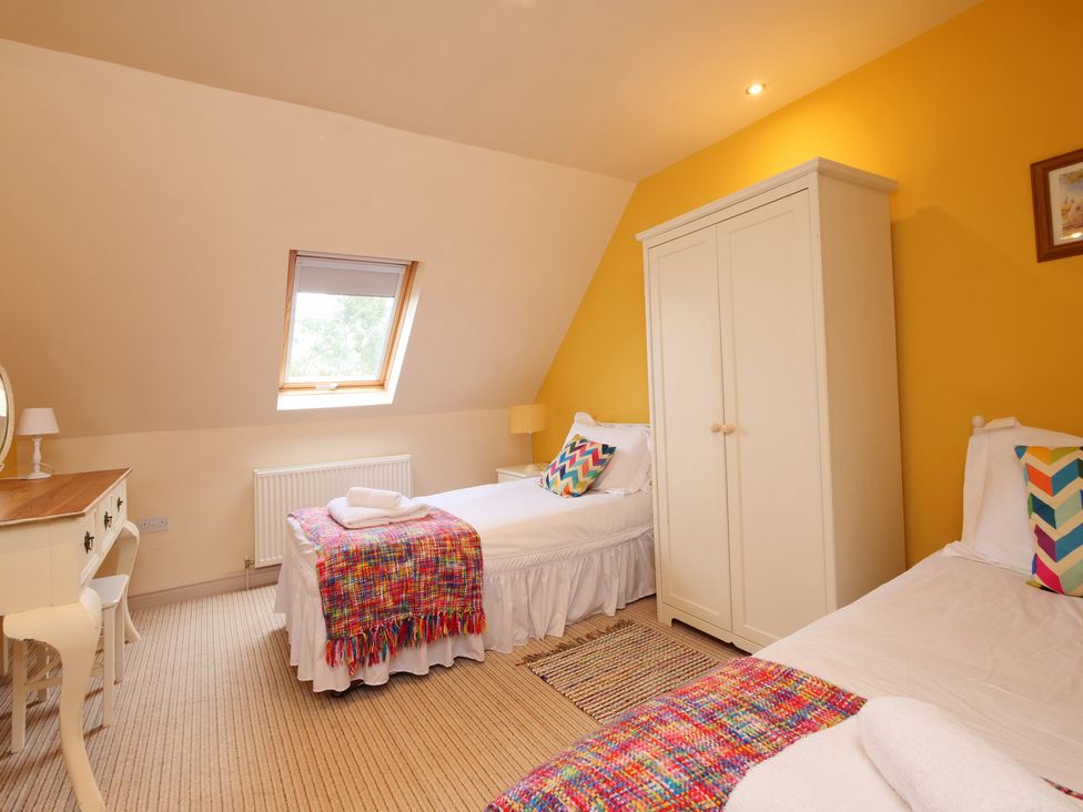 A bedroom with two beds and a wardrobe at Scoresby Cottage @ Summerfield Farm, Hawsker