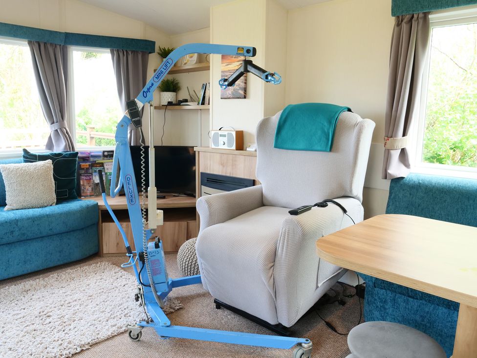 A living room with a lifting hoist next to an armchair at Abbey View @ Summerfield Farm, Hawsker