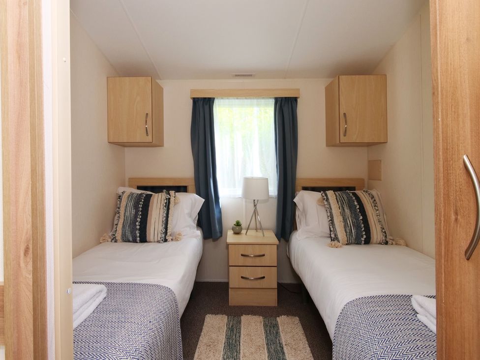 A bedroom with twin beds and a bedside table at Abbey View @ Summerfield Farm, Hawsker