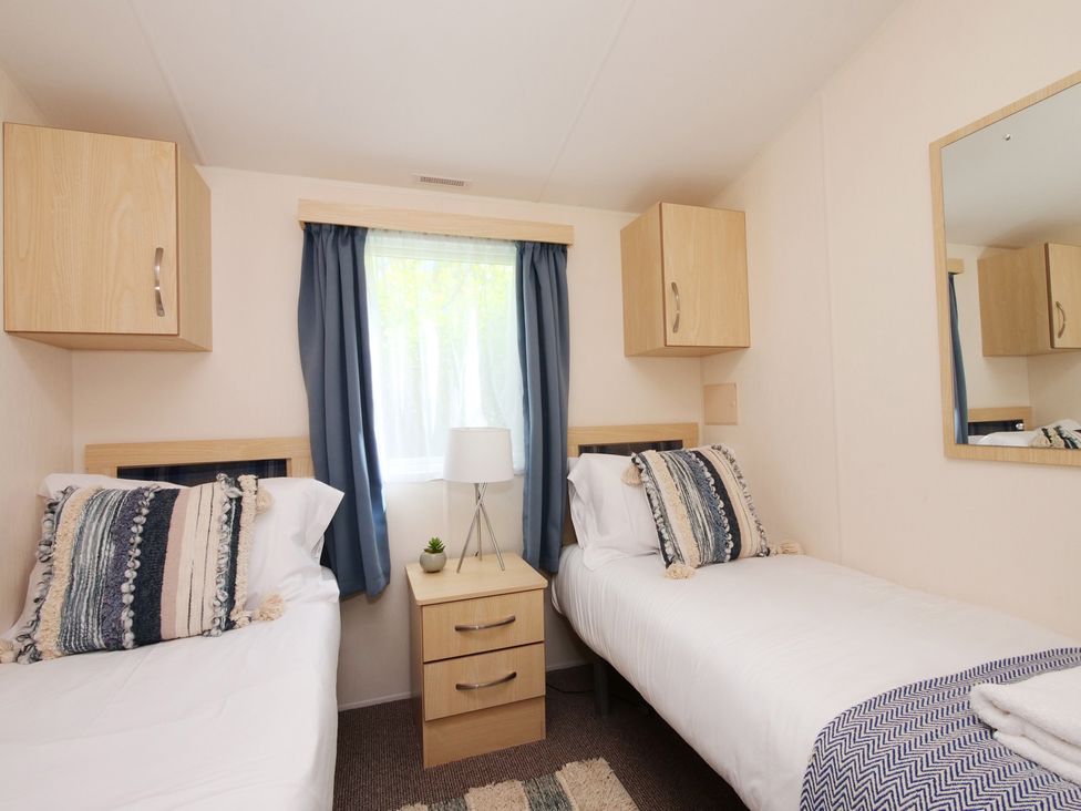 A bedroom with two single beds and a bedside table at Abbey View @ Summerfield Farm, Hawsker