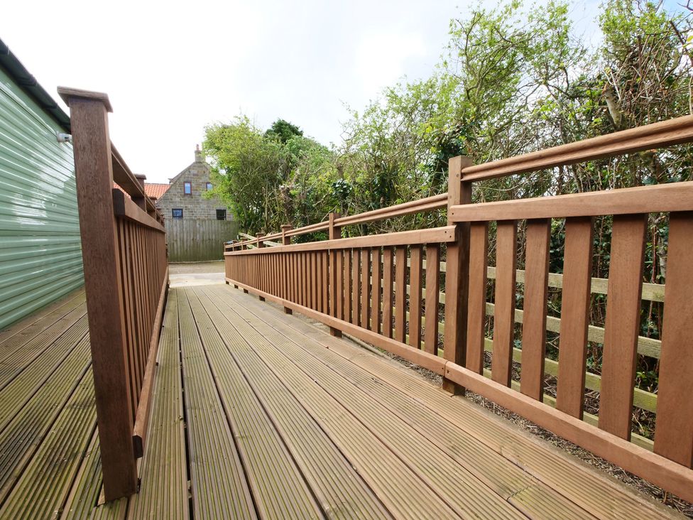 A decking area with a handrail and pathway at Abbey View @ Summerfield Farm Hawsker