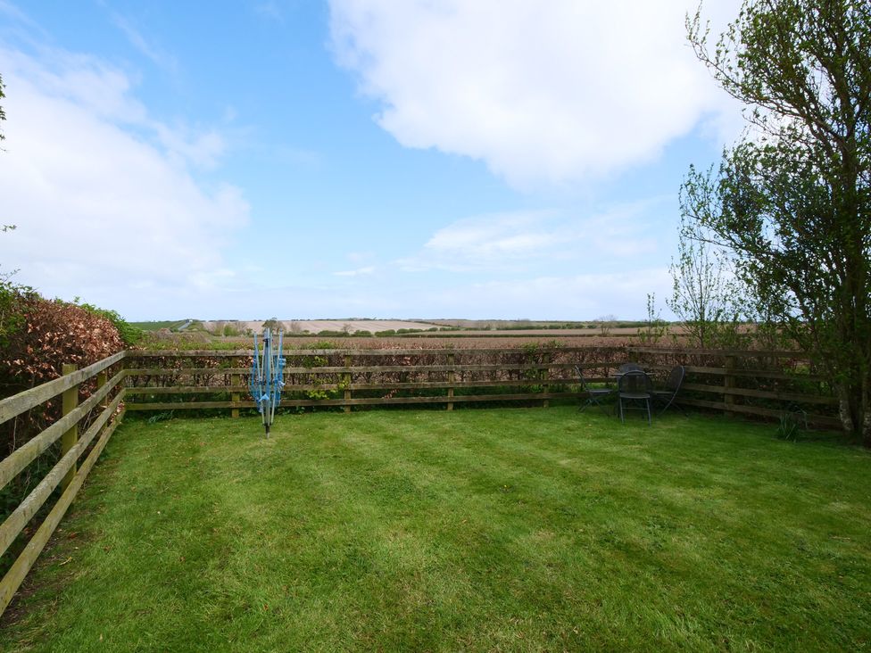 A garden with a chair and umbrella stand at Abbey View @ Summerfield Farm in Hawsker